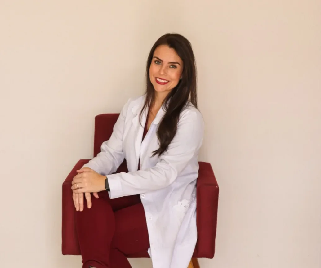 Josiéle sentada numa poltrona bordô, de jaleco branco